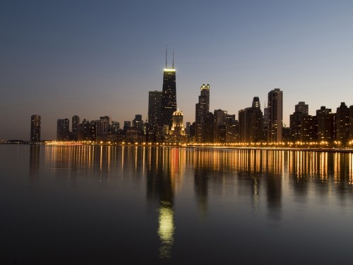 Image city skyline across body of water during night time