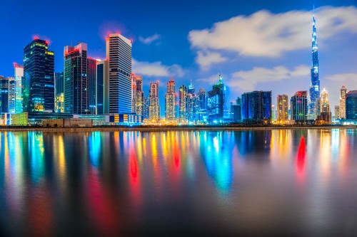 Image city skyline across body of water during night time