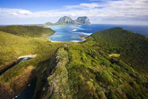 Image green mountain beside body of water during daytime