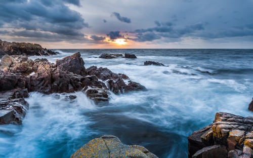 Image rocky shore with ocean waves under cloudy sky during daytime